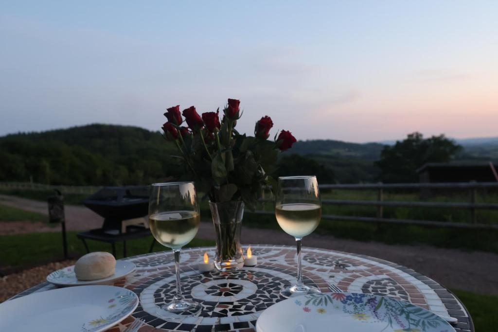 Sunset over the valley from the hut terrace, with roses and two glasses of wine on the table